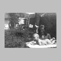 022-0463 Lieselotte Kristott, geb.Schulz, mit Sohn Frank im Garten bei Gustav Schulz. Hinten ist das Wohn- und Geschaeftshaus Herholz zu erkennen.jpg